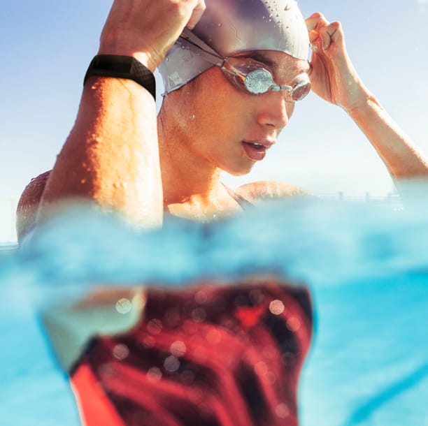 woman in a pool putting on her swim goggles